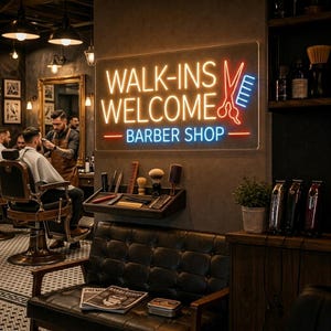 Op de afbeelding: Een rechthoekig neonbord aan de muur met de tekst WALK-INS WELCOME BARBER SHOP in geel en blauw, voorzien van een rode schaar en een blauwe kam. Onder het bord bevindt zich een plank met verzorgingsproducten en een zwarte leren bank.