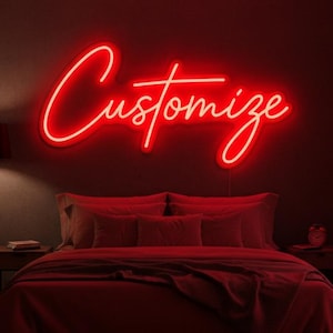 May include: A red neon sign reading "Customize" in a cursive font is mounted on a dark red wall. The sign is above a bed with red bedding. A nightstand and a small clock are visible.