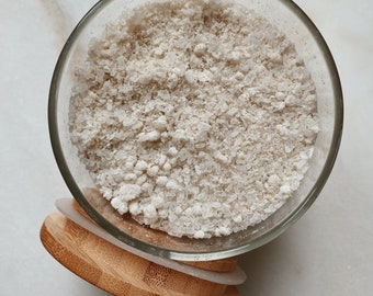 May include: A glass jar with a bamboo lid filled with white, granulated sugar.