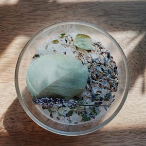 May include: A glass bowl filled with bath salts, dried lavender, eucalyptus leaves, and other herbs.