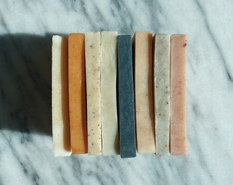 May include: A stack of eight different coloured bars of soap. The bars are arranged vertically and are all the same size. The bars are made from natural ingredients and are free from harsh chemicals.