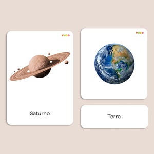 May include: Two illustrated cards with the names "Saturno" and "Terra" written below. The card on the left shows a brown planet with rings, and the card on the right shows a blue planet with white clouds.