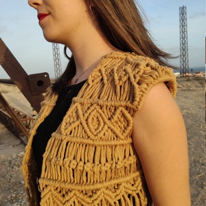 May include: A brown crocheted vest with a geometric pattern. The vest has a sleeveless design and is made of a soft, natural fiber.