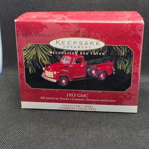以下が含まれることがあります： 赤い1953年型GMCトラックのオーナメント。コレクターズシリーズの一部で、オリジナルの箱に入っています。箱には「KEEPSAKE ORNAMENT」と「DÉCORATION DES FÊTES」の文字が書かれています。トラックの荷台にはクリスマスツリーが載っています。
