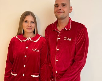 May include: Matching red velvet pyjamas with white trim and embroidered text. One set says "Mom" and the other says "Dad". The pyjamas have a button-up top and trousers.