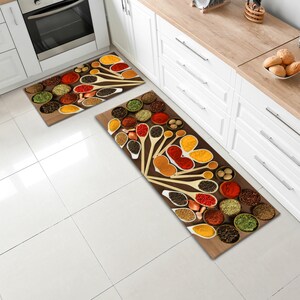 May include: Two kitchen rugs with a brown background and a design of various spices in wooden spoons and bowls. The spices are red, yellow, orange, green, and black.
