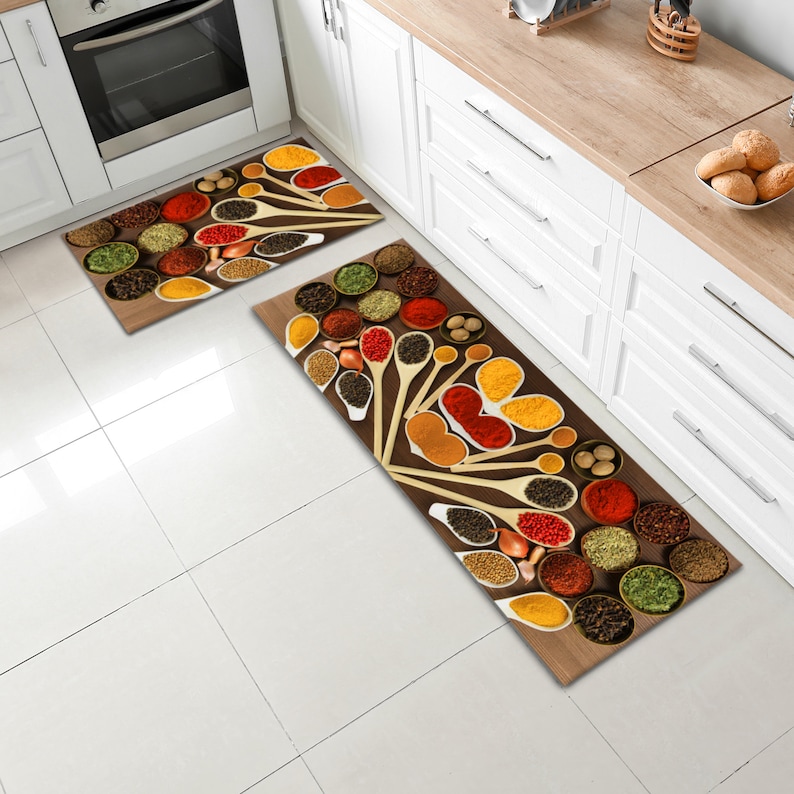 May include: Two kitchen rugs with a brown background and a design of various spices in wooden spoons and bowls. The spices are red, yellow, orange, green, and black.
