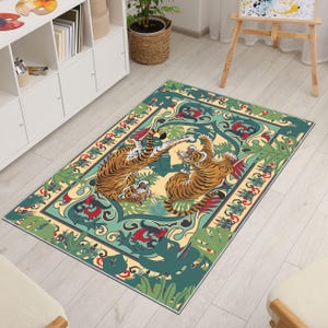 May include: Rectangular area rug featuring a design with two tigers in a playful pose. The rug has a cream-colored background with green, red, and blue decorative elements. The tigers are orange and black.