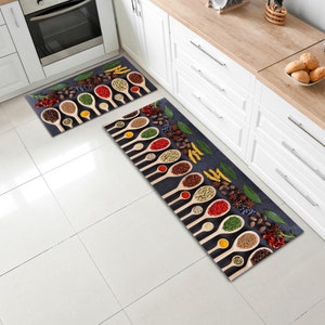 May include: Two kitchen rugs with a dark blue background and a pattern of wooden spoons filled with various spices. The spoons are arranged in rows and the spices are a variety of colours, including red, green, yellow, and brown.