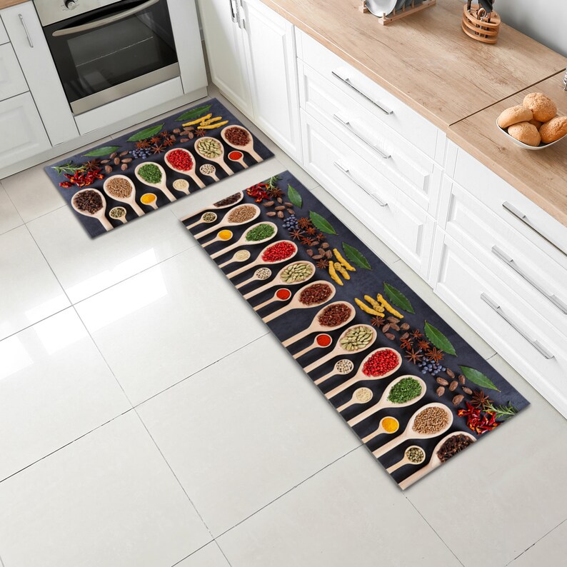 May include: Two kitchen rugs with a dark blue background and a pattern of wooden spoons filled with various spices. The spoons are arranged in rows and the spices are a variety of colours, including red, green, yellow, and brown.