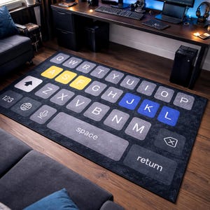 Puede incluir: Una alfombra rectangular diseñada para parecerse a un teclado de teléfono inteligente. La alfombra presenta teclas grises con letras blancas, teclas de acento amarillas y azules. La alfombra está colocada sobre un suelo de madera.
