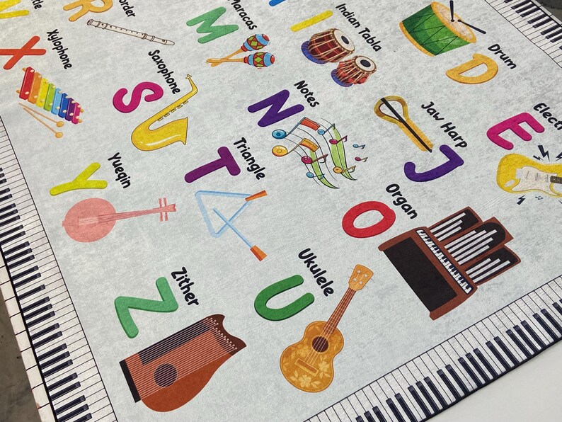 May include: A light gray educational rug featuring musical instruments and the alphabet. Instruments include a xylophone, saxophone, ukulele, and organ. The rug has a piano keyboard border and colorful letters.