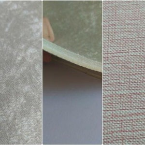 Puede incluir: Tres muestras de tela, una es gris claro con una textura sutil, otra es gris claro con una textura lisa y la &uacute;ltima es una tela tejida blanca y rosa claro.