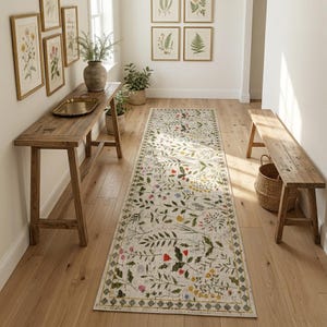 Pode incluir: Um tapete longo e retangular com um padrão floral num corredor. O tapete apresenta um fundo creme com folhas verdes e flores coloridas. O corredor é mobilado com móveis de madeira e estampas botânicas emolduradas.