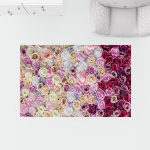 Puede incluir: Una alfombra floral con un esquema de color rosa, blanco y crema. La alfombra est&aacute; hecha de un material suave y mullido y presenta una variedad de flores diferentes.