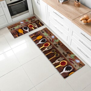 May include: Two kitchen rugs featuring a brown wooden background with various spices in wooden spoons. The rugs are rectangular and have a burlap texture.