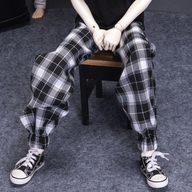 May include: Black and white plaid pants with elastic cuffs. The pants are loose fitting and have a casual style.