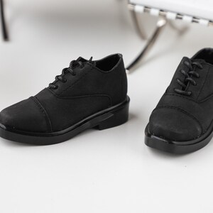 Puede incluir: Un par de zapatos negros de cuero con cordones, punta redonda y suela gruesa.