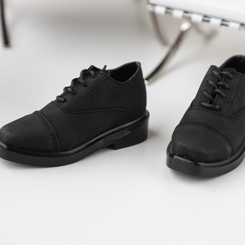 Puede incluir: Un par de zapatos negros de cuero con cordones, punta redonda y suela gruesa.