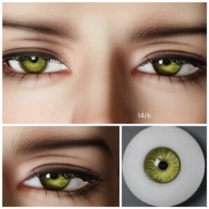 May include: Close-up of a pair of green glass eyes for dolls. The eyes are set in a white plastic base and have a black pupil. The eyes are 14/6 size.