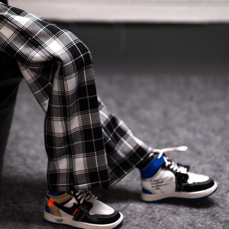 May include: A pair of black and white plaid pants with a white and black high-top sneaker with blue accents and the word "AIR" on the side.