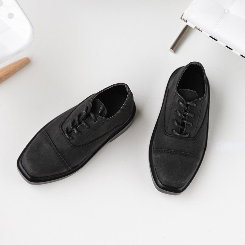 Puede incluir: Un par de zapatos negros de cuero con cordones, punta redonda y suela gruesa.