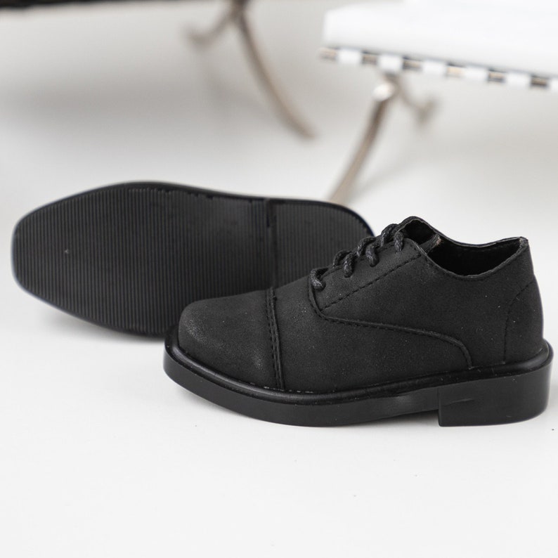 Puede incluir: Un par de zapatos negros de cuero con cordones, punta redonda y suela gruesa.