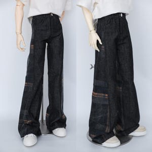 Könnte beinhalten: Dunkelblaue Jeanshose mit weitem Bein. Die Hose hat braune und graue Karomuster-Akzente an den Seiten. Die Hose wird an einer Puppe mit weißen Turnschuhen gezeigt.