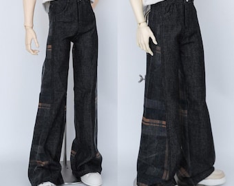 Può includere: Pantaloni in denim blu scuro con un design a gamba larga. I pantaloni presentano accenti a quadri marroni e grigi sui lati. I pantaloni sono mostrati su una bambola con scarpe da ginnastica bianche.