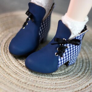 May include: A pair of blue ankle boots with white and blue gingham fabric accents. The boots have black laces and a rounded toe.