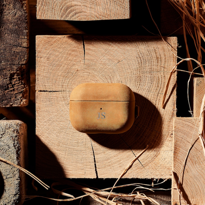 May include: A brown leather case for wireless earbuds with the initials "JS" embossed on the front.