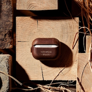 May include: A brown leather case for AirPods with the text "Cotswold Wears" embossed on the front.