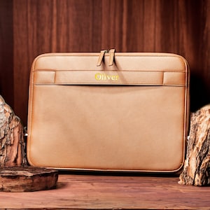 May include: A brown leather laptop sleeve with a zipper closure and the name "Oliver" embossed in gold lettering.