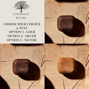 May include: Three leather Airpod cases with different initials in gold foil. The cases are on a wooden background. Choose your color and text: Option 1 - Gold, Option 2 - Silver, Option 3 - No Foil.