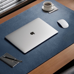May include: A blue leather desk mat with a silver laptop, a white mouse, a cup of coffee, and a pen and notepad. The desk mat has the name "JAMIE" embossed on it.