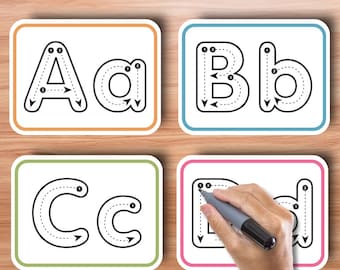 Puede incluir: Cuatro tarjetas blancas con contornos negros y líneas punteadas para trazar las letras A, a, B, b, C, c y D, d. Las tarjetas están sobre un fondo de madera. Una mano está trazando la letra D con un marcador gris.