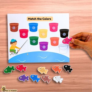 May include: A color matching game for kids featuring a printable worksheet with buckets and fish. The worksheet says "Match the Colors". The fish are red, orange, yellow, green, blue, purple, brown, black, and white.