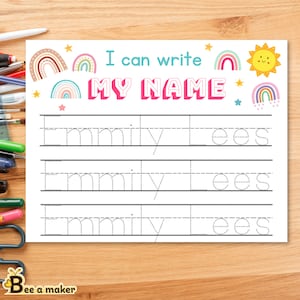 Puede incluir: Una hoja de trabajo blanca con el texto "I can write MY NAME" en azul y rosa. La hoja de trabajo tiene ilustraciones de arcoíris y estrellas. Debajo del texto hay líneas punteadas para escribir el nombre "Emmily Lees".