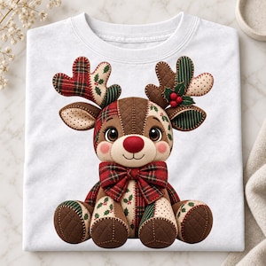 May include: A white t-shirt featuring a graphic of a patchwork-style reindeer. The reindeer has a red nose, a red plaid bow tie, and antlers decorated with green holly leaves and red berries. The design uses various fabric patterns.