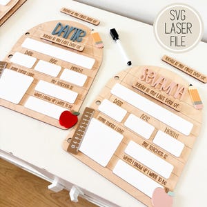 May include: Two arched wooden school memory boards with white dry-erase sections for date, age, height, teacher, and interests. Each board features a name cutout, a pencil-shaped accent, and an apple shape. Includes a black dry-erase marker.