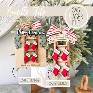 Puede incluir: Adornos navideños de madera con calcetines rojos colgados de una escalera. Uno dice "Merry Christmas", el otro "The Reynolds Family". Ambos tienen una cinta a rayas rojas y blancas. Los adornos están cortados con láser.