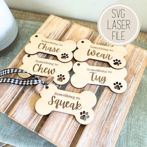 May include: Five wooden dog bone shaped ornaments with laser engraved text. The text reads "Something to Chase", "Something to Chew", "Something to Wear", "Something to Tug", and "Something to Squeak".