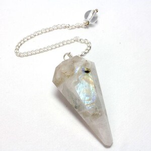 Può includere: Un pendolo di cristallo bianco con colori arcobaleno iridescenti. Il pendolo è attaccato a una catena d'argento con una perla di cristallo trasparente in cima.