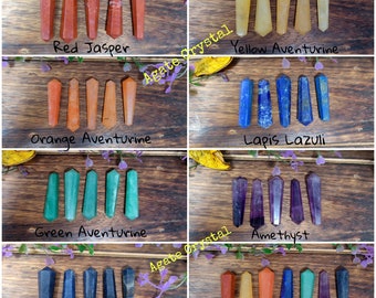 May include: Seven chakra crystal wands in a grid. The wands are red, orange, yellow, green, blue, indigo, and violet. The wands are arranged in a grid on a wooden surface. The text "Agate Crystal" is written on the image.