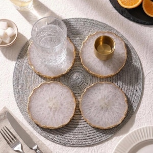 Top view flatlay of four natural white agate coasters set with glassware on circular grey placemat
