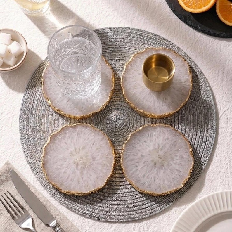Top view flatlay of four natural white agate coasters set with glassware on circular grey placemat