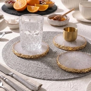 Glass of water and brass cup placed on white agate slice coasters for luxury table setting decor