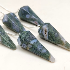 May include: Five green and white agate crystal pendulums on silver chains. The pendulums are all pointed at the bottom and have a variety of patterns.