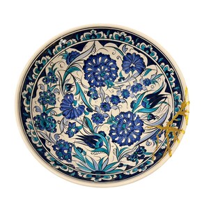 Könnte beinhalten: Ein runder Keramikteller mit einem floralen Design in Blau- und Türkistönen auf cremefarbenem Hintergrund. Der Teller hat einen dunkelblauen Rand und goldene Akzente. Dekoratives Geschirr.