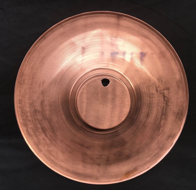 May include: A copper-coloured metal plate with a circular indentation in the centre. The plate has a smooth, slightly textured surface.